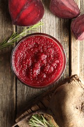 Photo of Fresh beetroot smoothie in glass, rosemary and cut vegetable on wooden table, flat lay