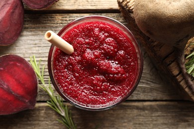 Photo of Fresh beetroot smoothie in glass, rosemary and cut vegetable on wooden table, flat lay