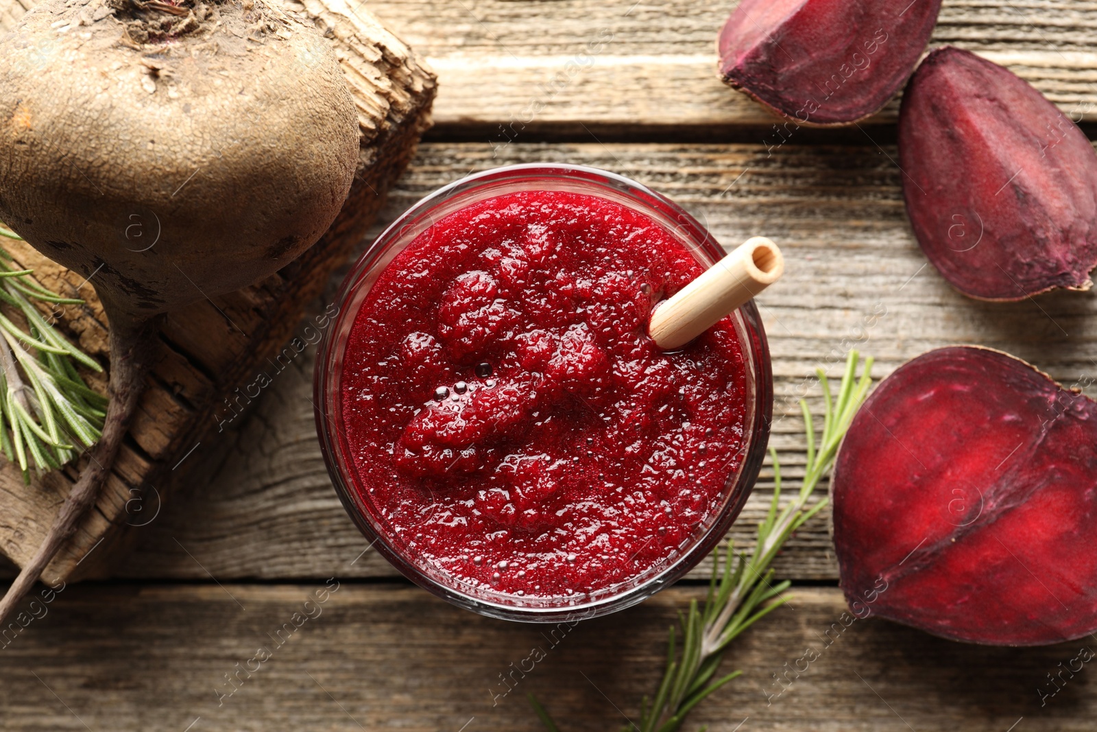 Photo of Fresh beetroot smoothie in glass, rosemary and cut vegetable on wooden table, flat lay