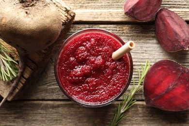 Photo of Fresh beetroot smoothie in glass, rosemary and cut vegetable on wooden table, flat lay