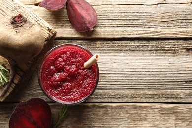 Photo of Fresh beetroot smoothie in glass, rosemary and cut vegetable on wooden table, flat lay. Space for text