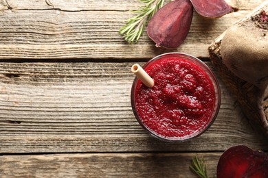 Photo of Fresh beetroot smoothie in glass, rosemary and cut vegetable on wooden table, flat lay. Space for text