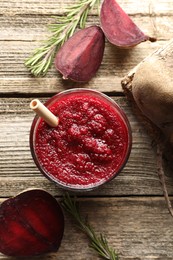 Photo of Fresh beetroot smoothie in glass, rosemary and cut vegetable on wooden table, flat lay