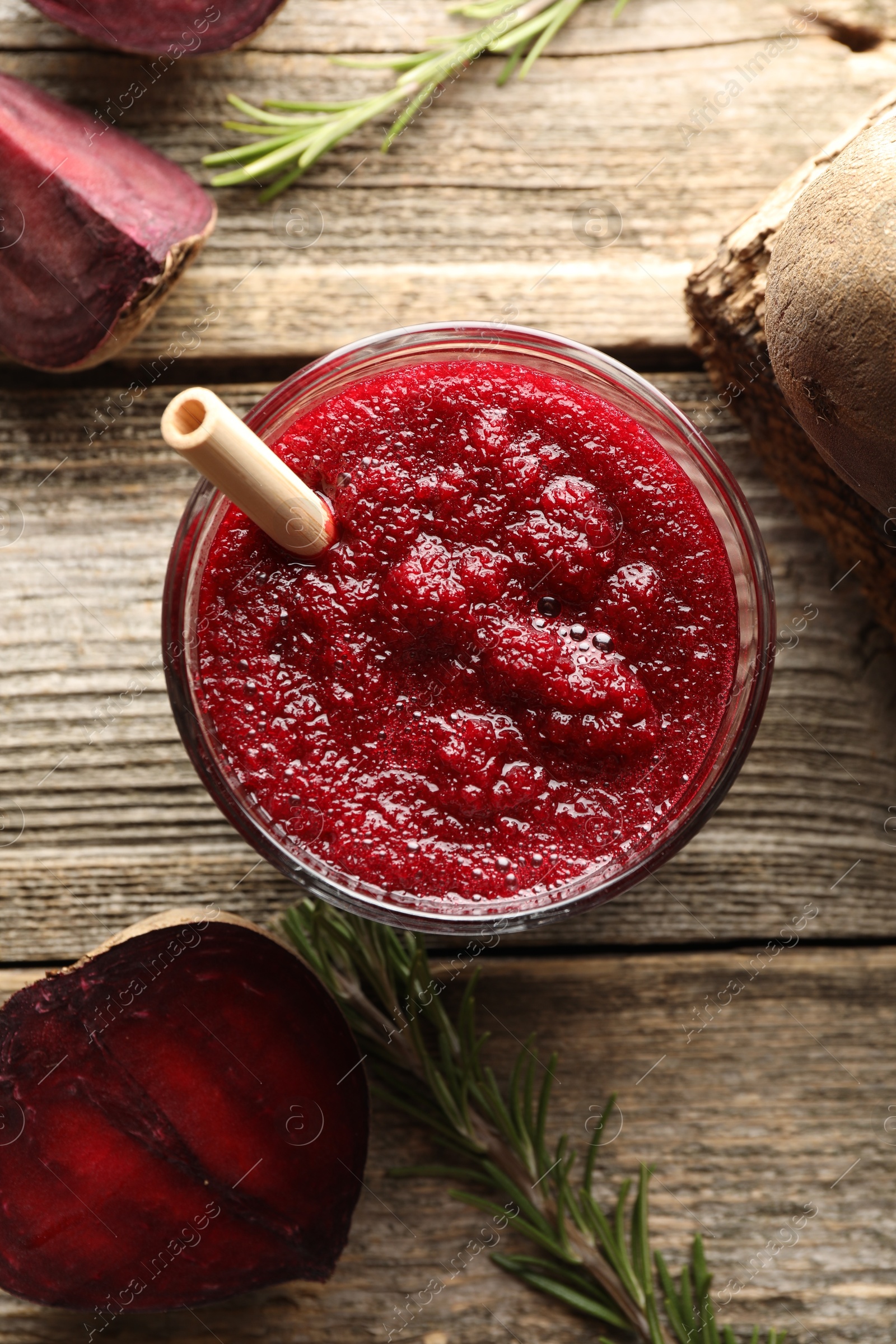 Photo of Fresh beetroot smoothie in glass, rosemary and cut vegetable on wooden table, flat lay