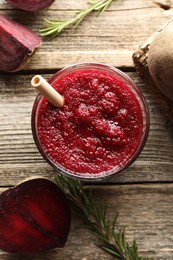 Photo of Fresh beetroot smoothie in glass, rosemary and cut vegetable on wooden table, flat lay