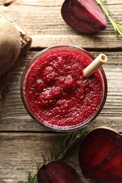 Photo of Fresh beetroot smoothie in glass, rosemary and cut vegetable on wooden table, flat lay