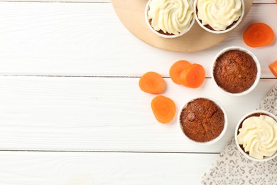 Photo of Tasty carrot muffins and fresh vegetable on white wooden table, flat lay. Space for text