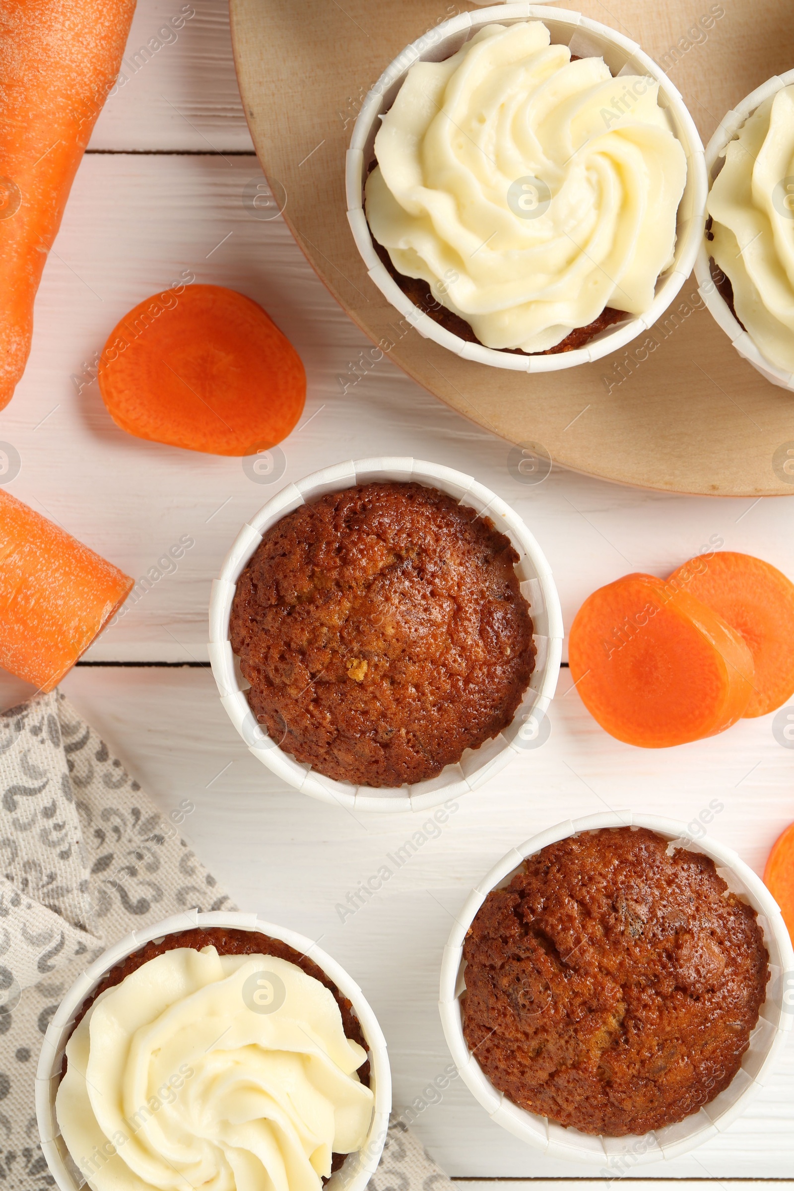 Photo of Tasty carrot muffins and fresh vegetables on white wooden table, flat lay