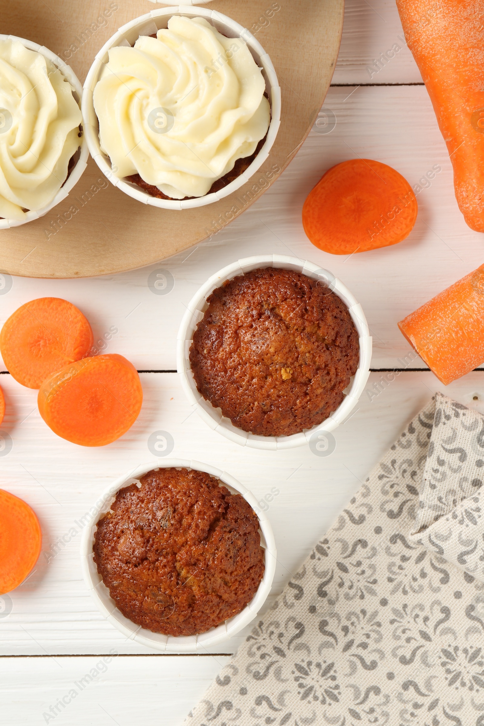 Photo of Tasty carrot muffins and fresh vegetables on white wooden table, flat lay