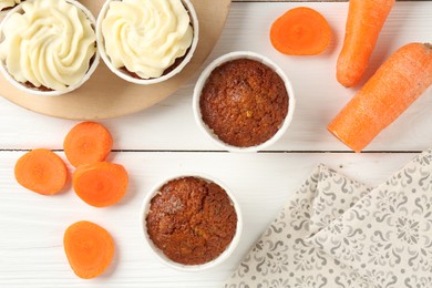 Photo of Tasty carrot muffins and fresh vegetables on white wooden table, flat lay