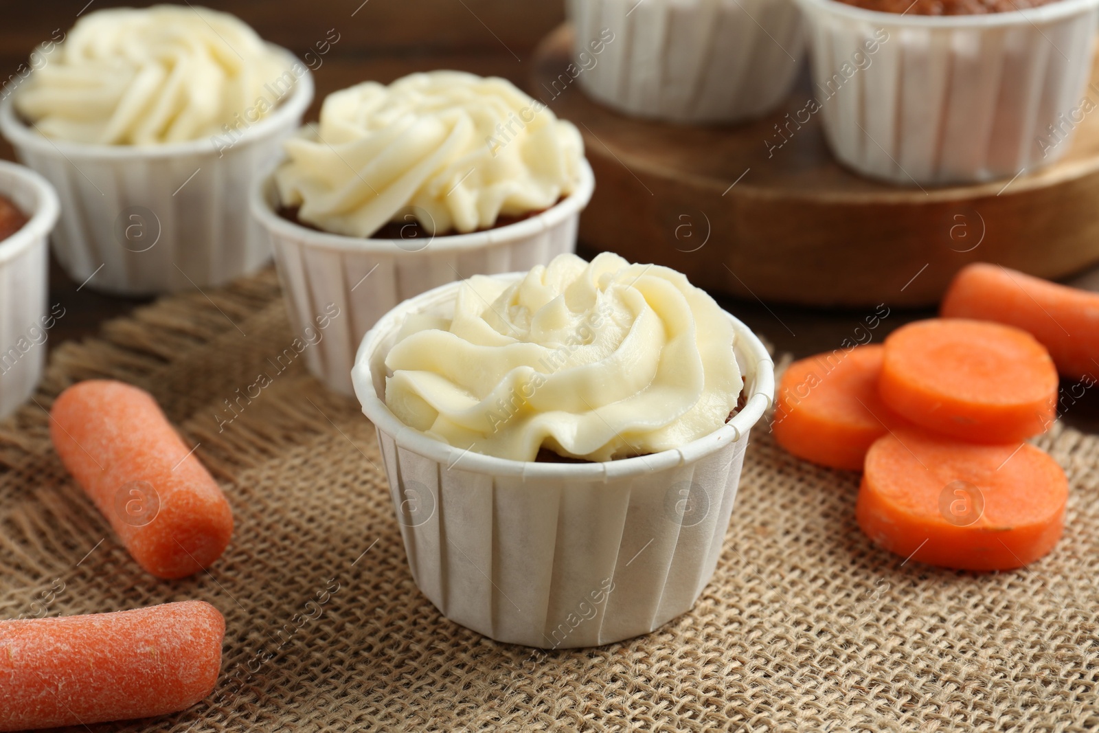 Photo of Tasty carrot muffins with cream and fresh vegetables on table, closeup