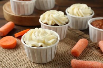 Photo of Tasty carrot muffins with cream and fresh vegetables on table, closeup