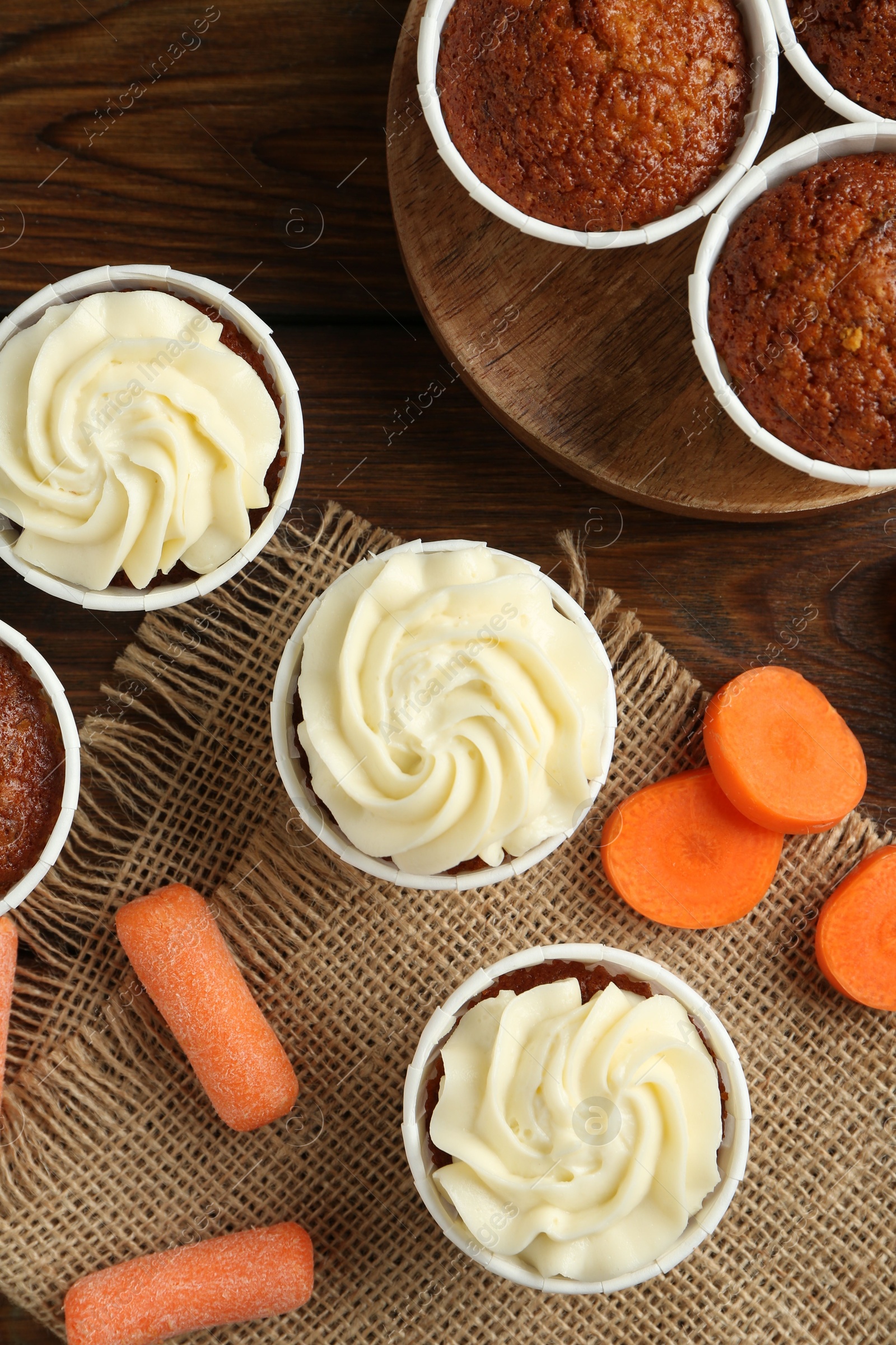 Photo of Tasty carrot muffins and fresh vegetables on wooden table, flat lay