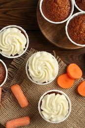 Photo of Tasty carrot muffins and fresh vegetables on wooden table, flat lay