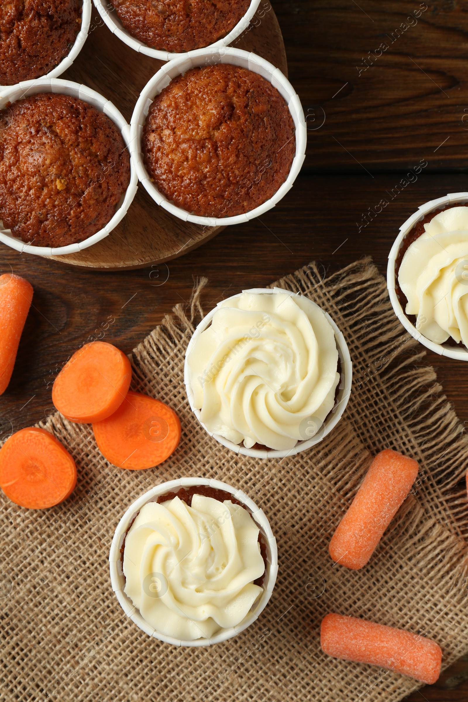 Photo of Tasty carrot muffins and fresh vegetables on wooden table, flat lay