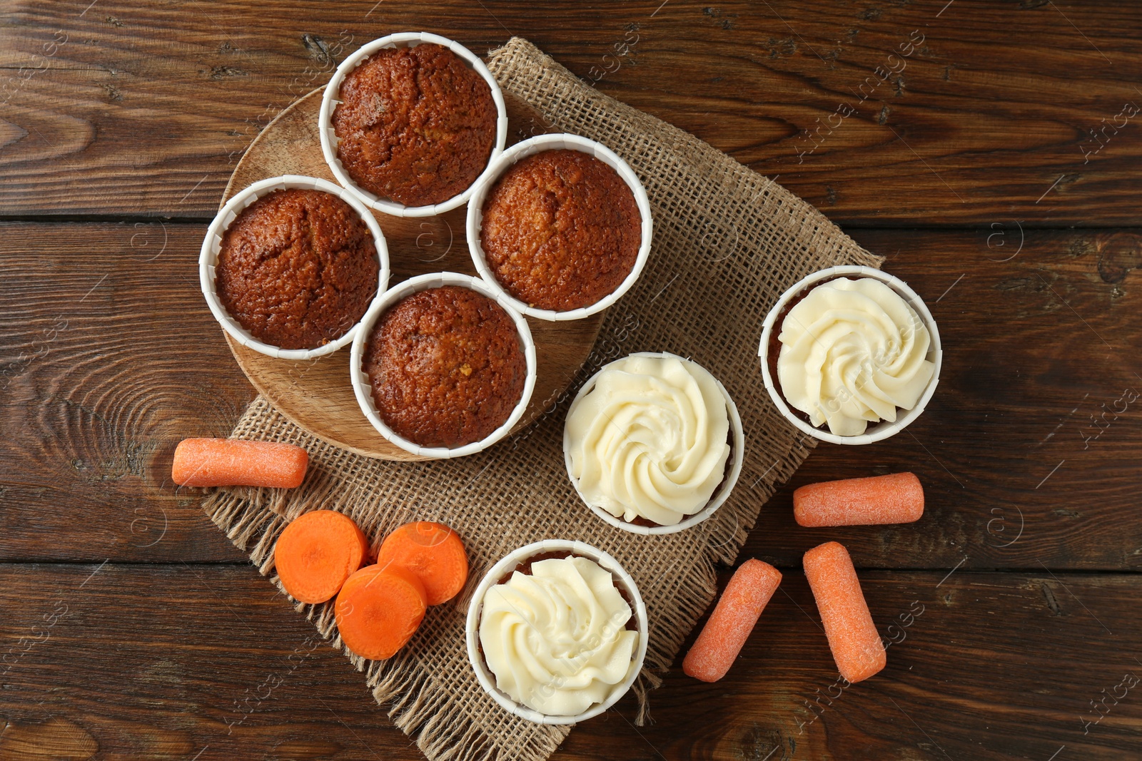 Photo of Tasty carrot muffins and fresh vegetables on wooden table, flat lay