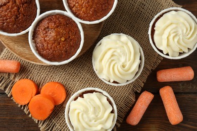 Photo of Tasty carrot muffins and fresh vegetables on wooden table, flat lay