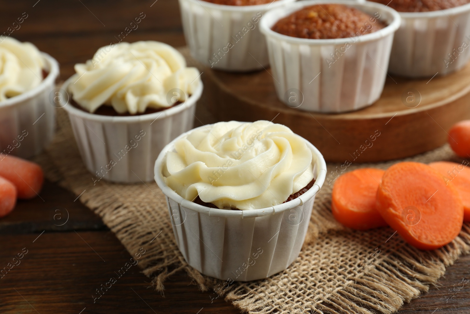 Photo of Tasty carrot muffins and fresh vegetable on wooden table, closeup