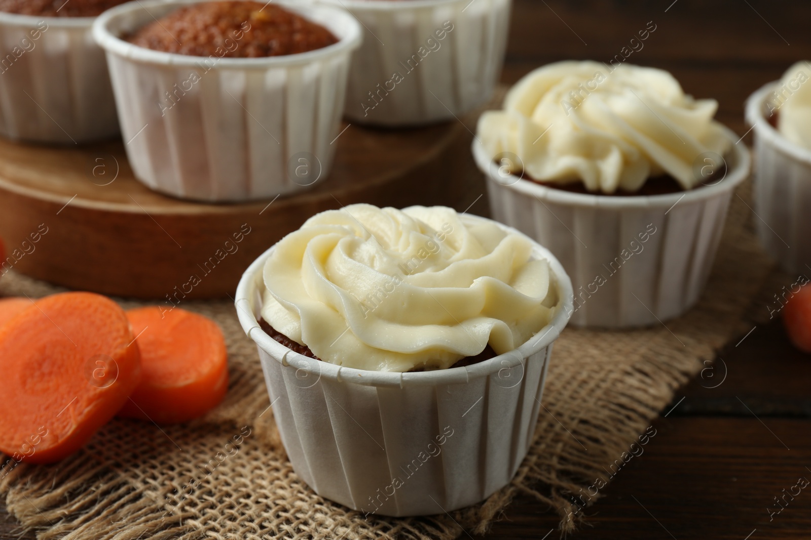 Photo of Tasty carrot muffins and fresh vegetable on wooden table, closeup