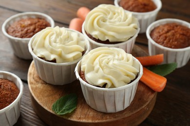 Photo of Tasty carrot muffins and fresh vegetable on wooden table, closeup