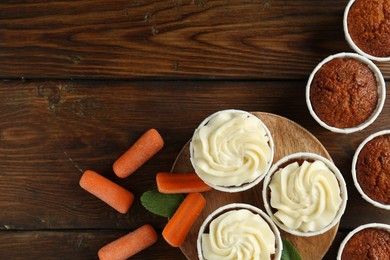 Photo of Tasty carrot muffins and fresh vegetables on wooden table, flat lay. Space for text