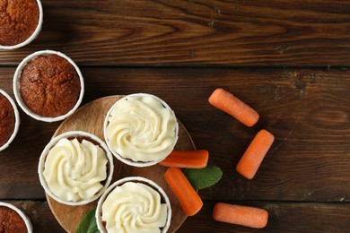 Photo of Tasty carrot muffins and fresh vegetables on wooden table, flat lay. Space for text