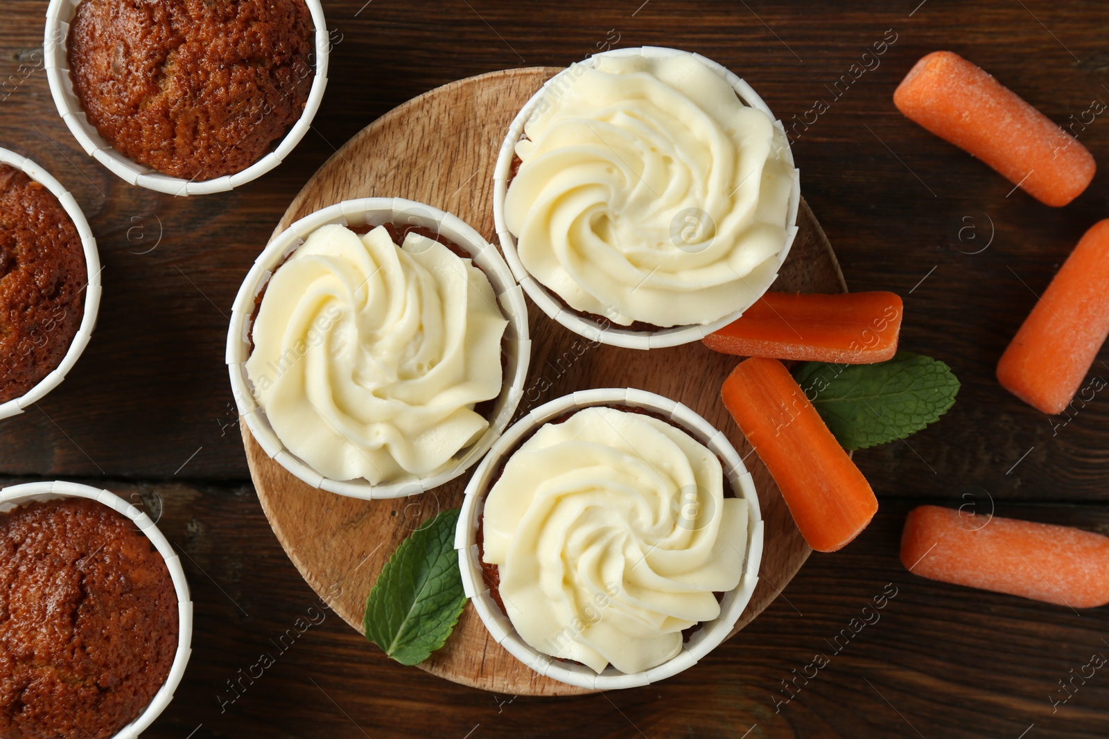 Photo of Tasty carrot muffins and fresh vegetables on wooden table, flat lay