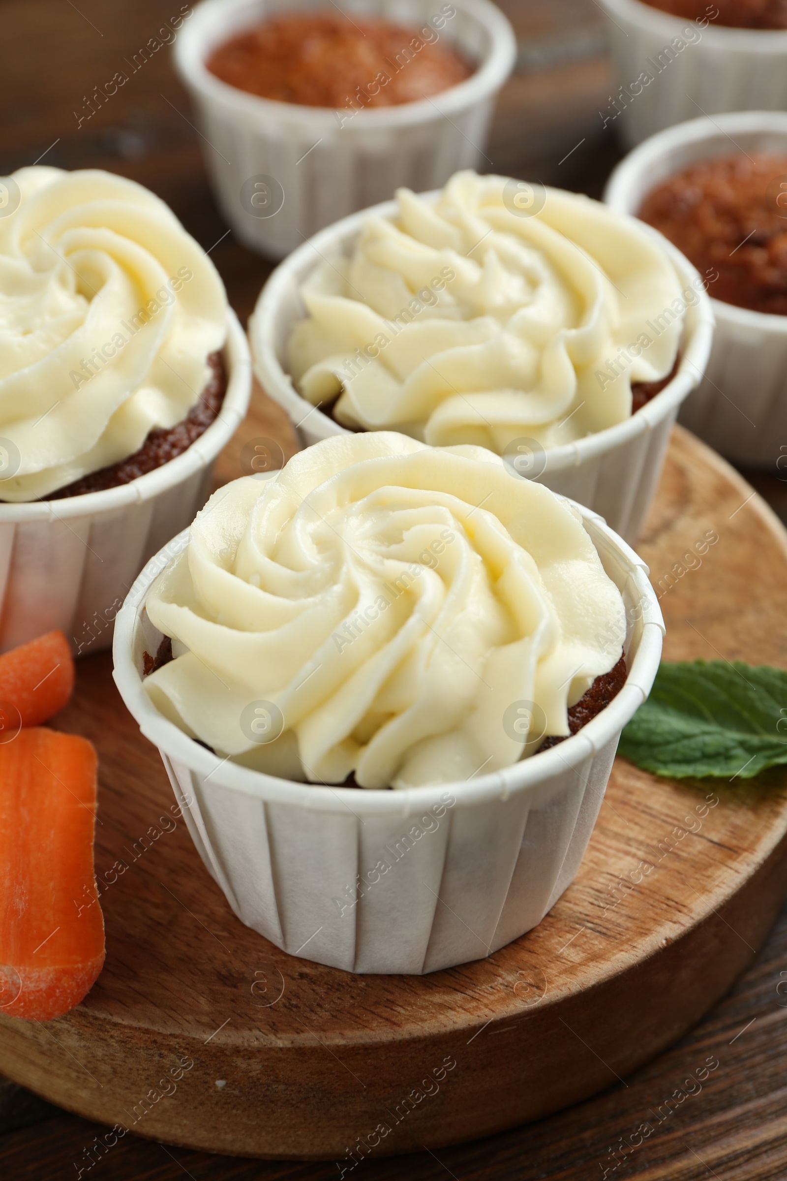 Photo of Tasty carrot muffins and fresh vegetable on wooden table, closeup