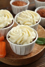 Photo of Tasty carrot muffins and fresh vegetable on wooden table, closeup