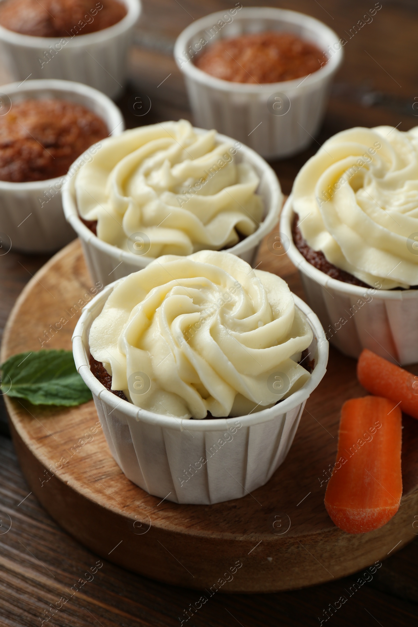 Photo of Tasty carrot muffins and fresh vegetable on wooden table, closeup