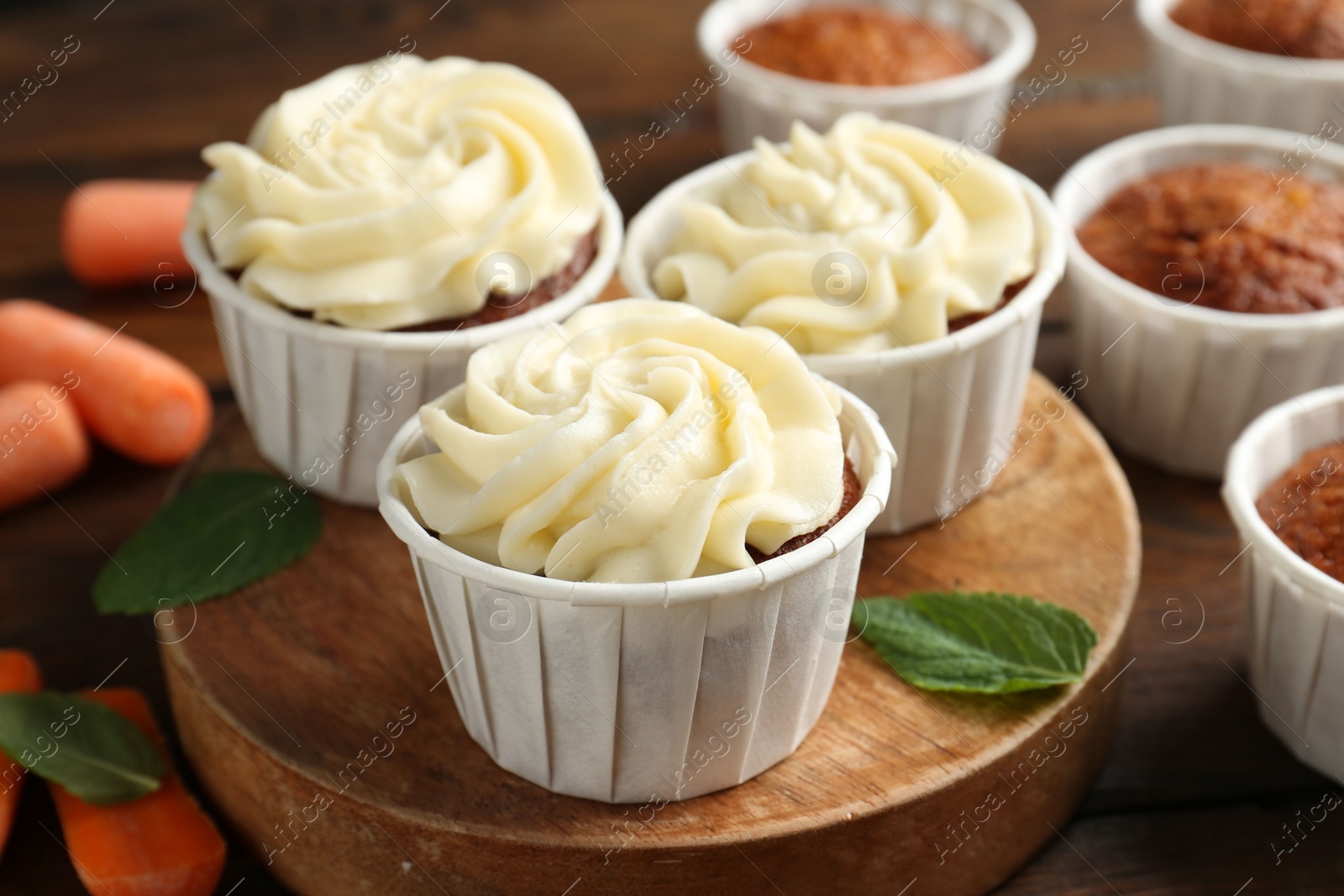 Photo of Tasty carrot muffins and fresh vegetables on wooden table, closeup