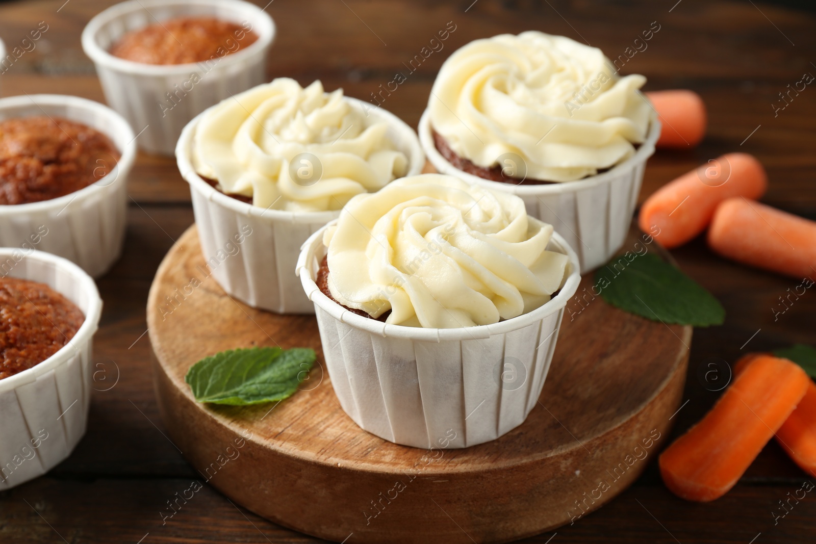 Photo of Tasty carrot muffins and fresh vegetables on wooden table, closeup