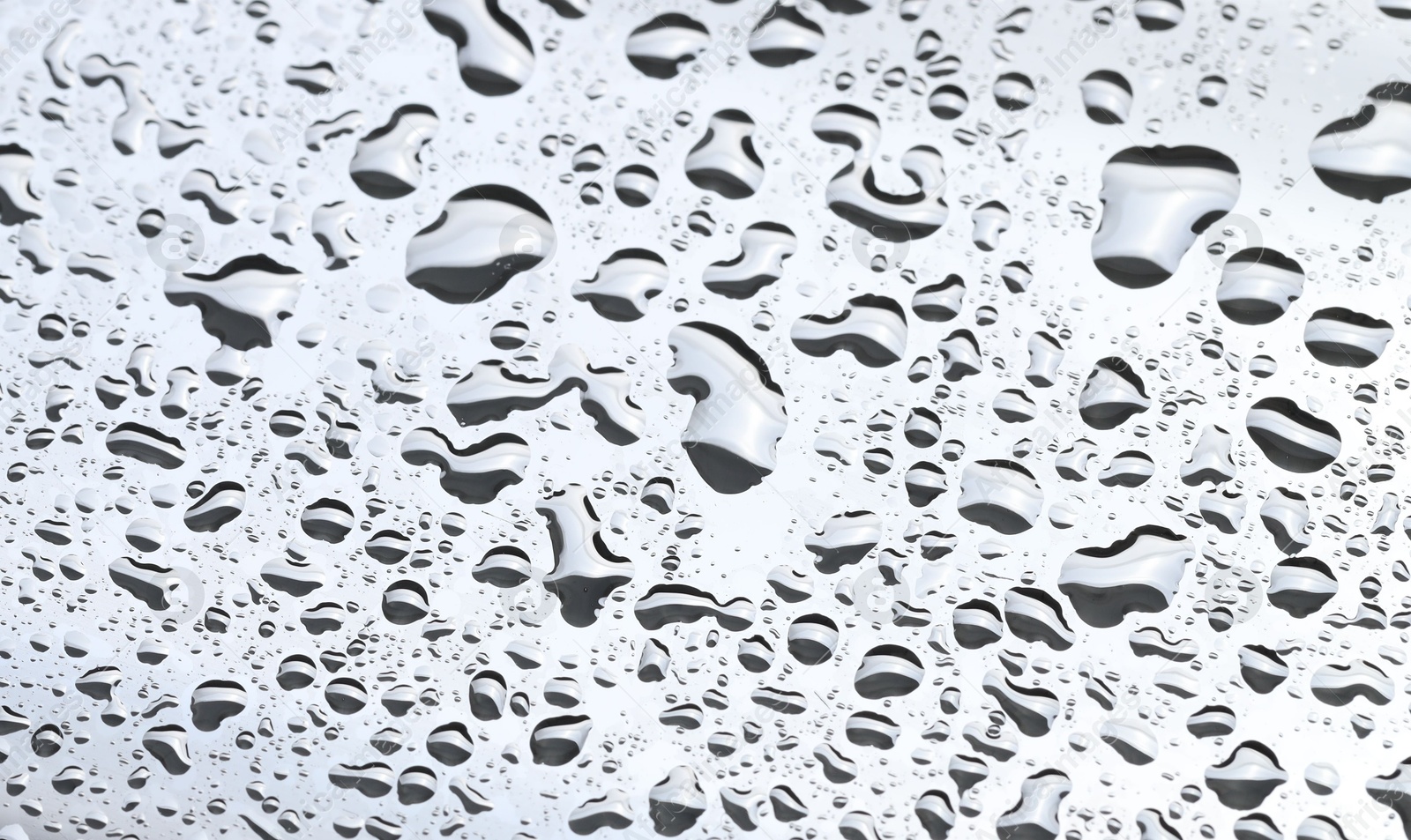 Photo of Water drops on light grey glass surface, closeup