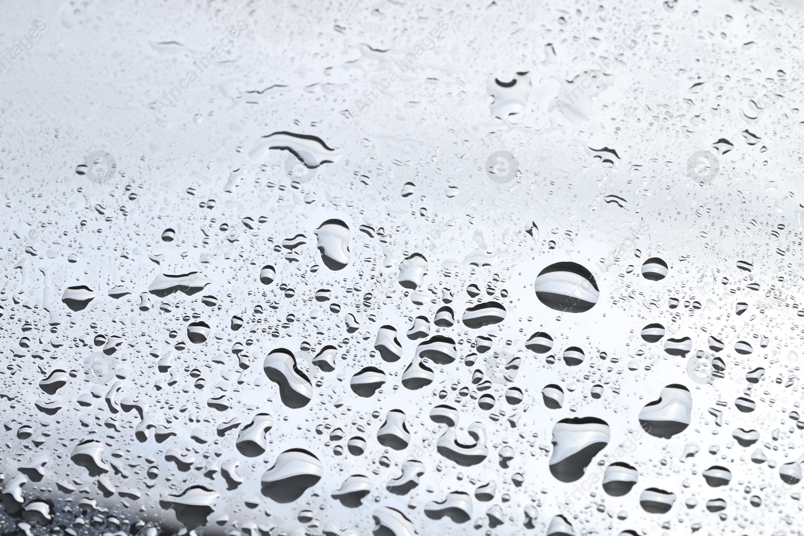 Photo of Water drops on light grey glass surface, closeup