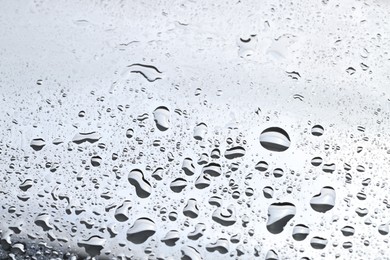 Water drops on light grey glass surface, closeup