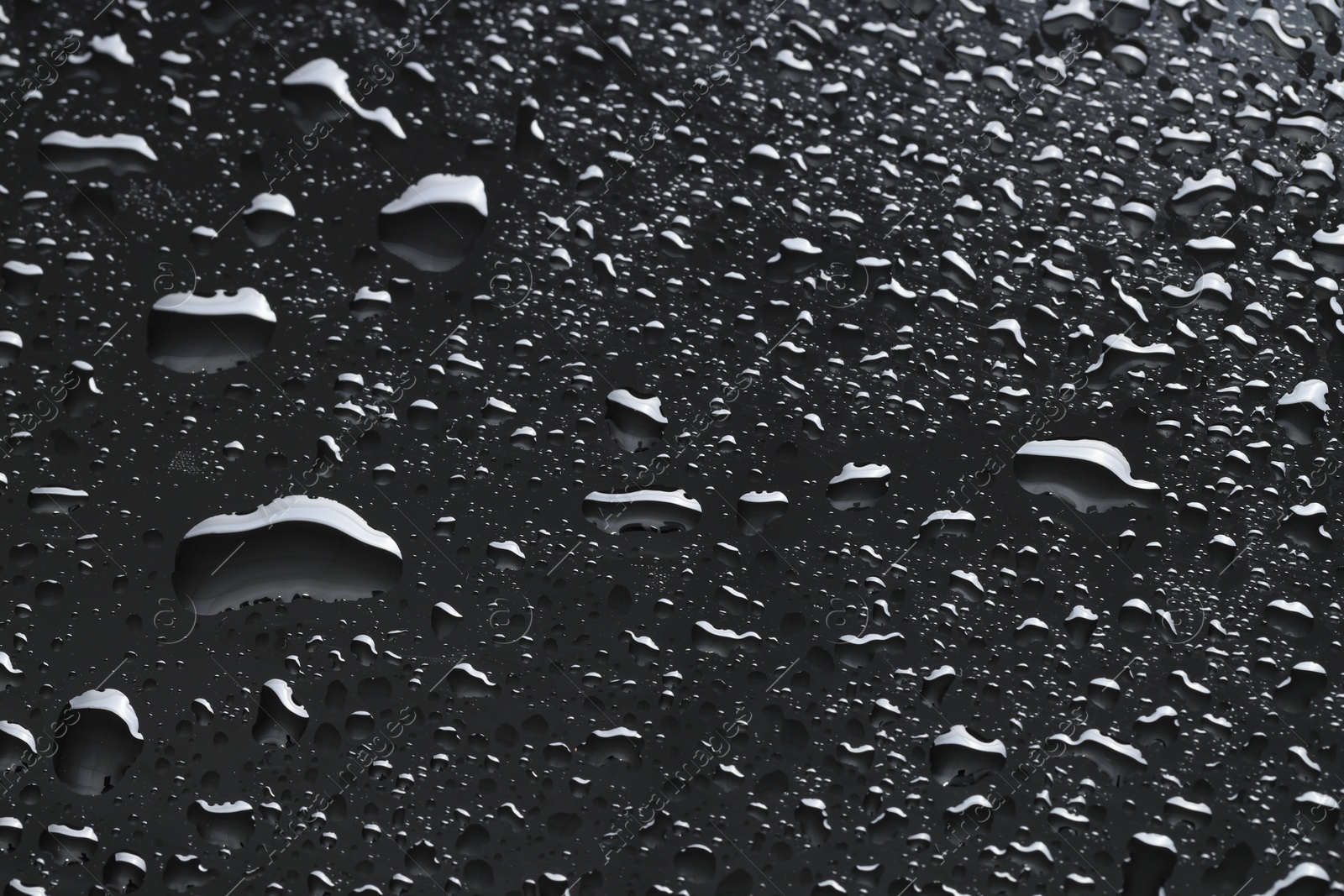 Photo of Water drops on dark grey glass surface, closeup