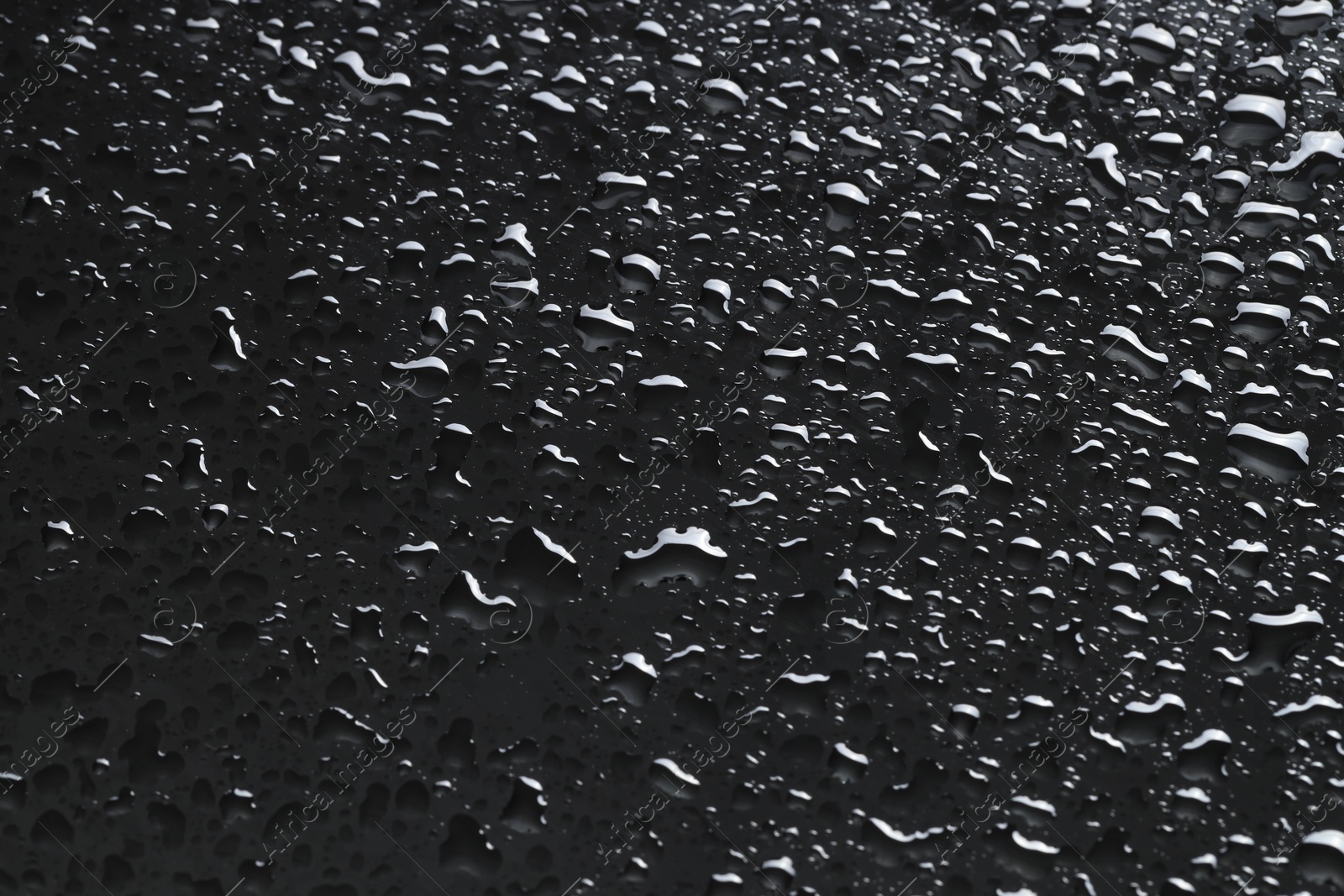 Photo of Water drops on dark grey glass surface, closeup