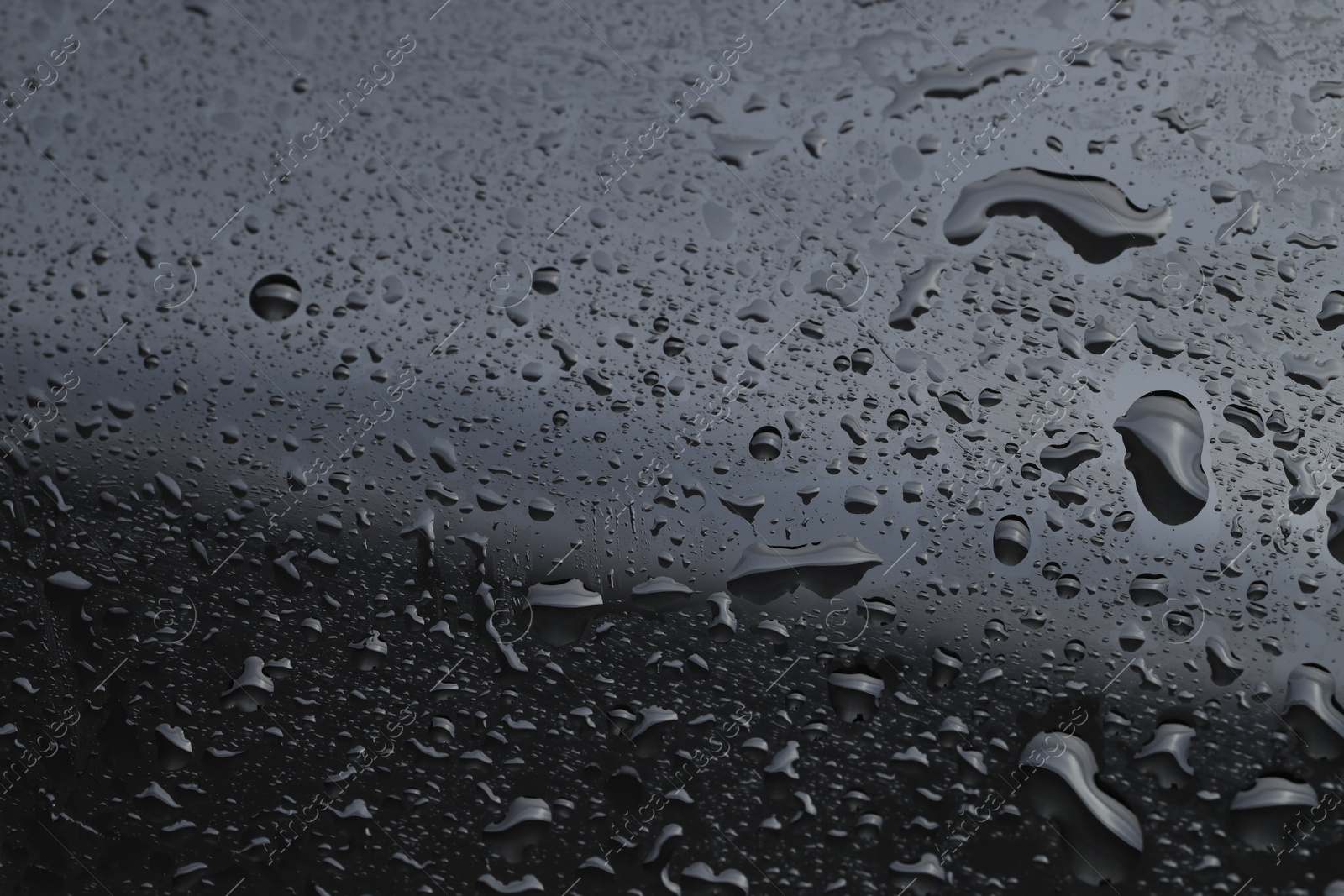 Photo of Water drops on grey glass surface, closeup