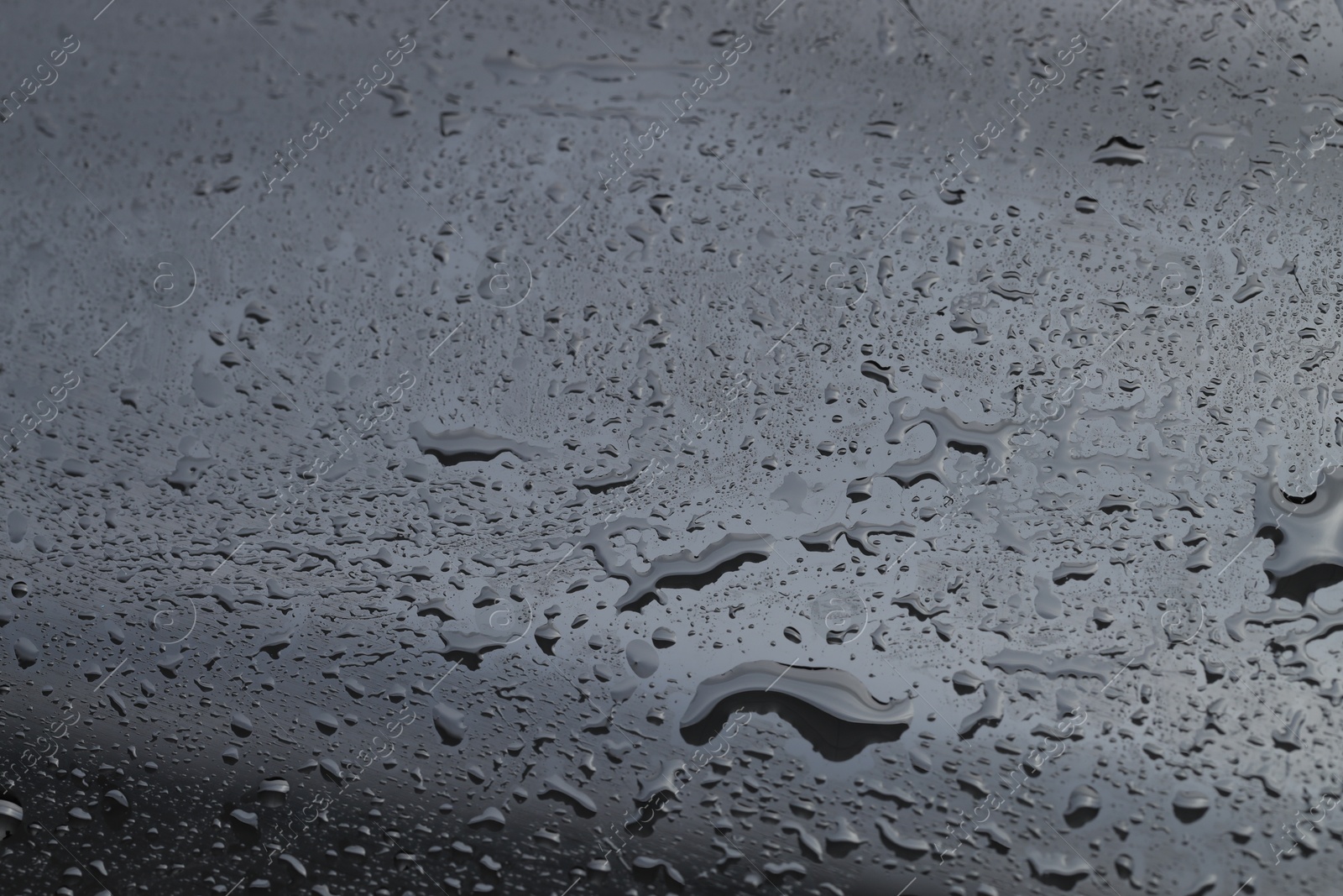 Photo of Water drops on grey glass surface, closeup