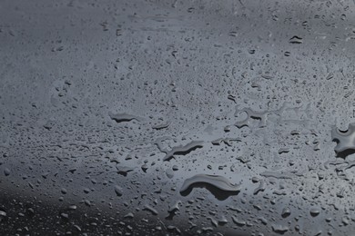 Water drops on grey glass surface, closeup