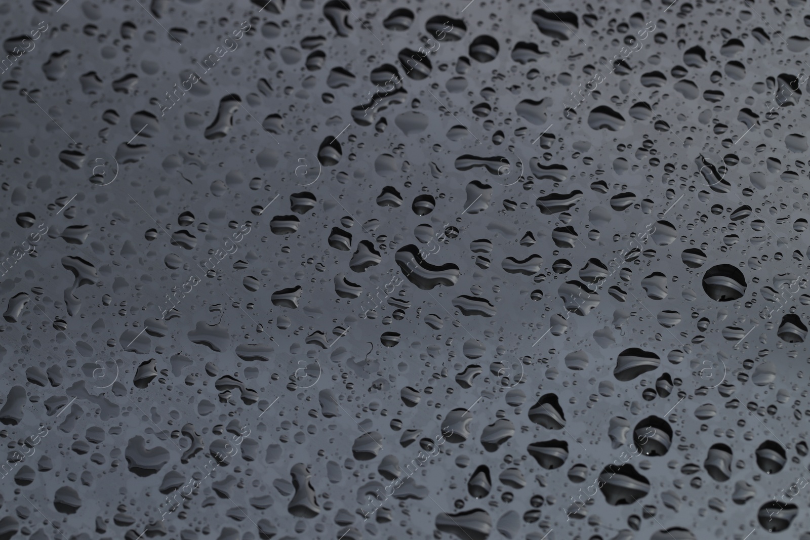 Photo of Water drops on grey glass surface, closeup