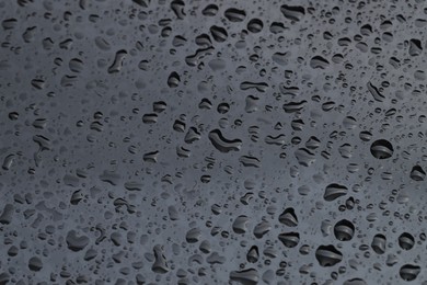 Photo of Water drops on grey glass surface, closeup