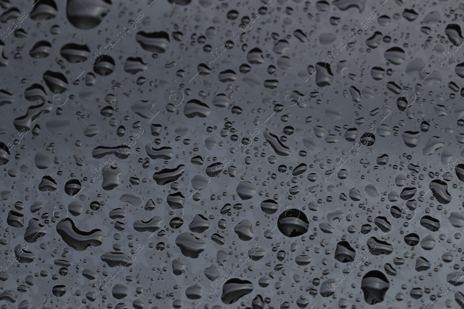 Photo of Water drops on grey glass surface, closeup