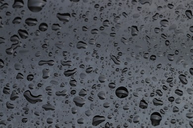 Photo of Water drops on grey glass surface, closeup