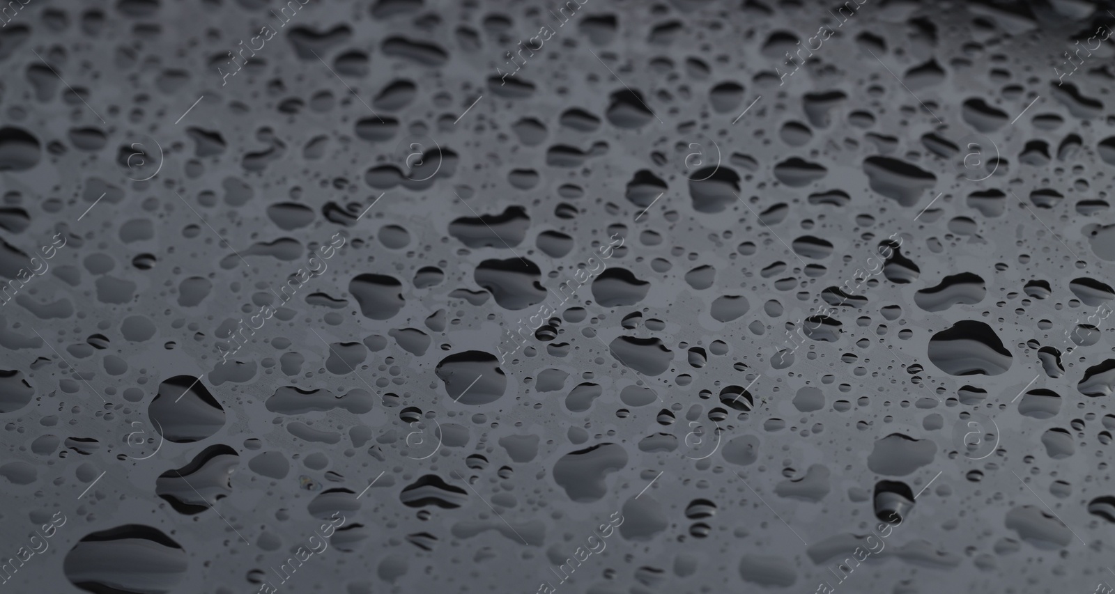 Photo of Water drops on grey glass surface, closeup