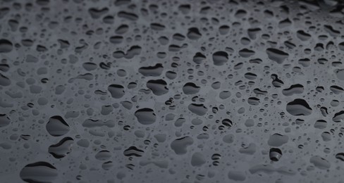 Photo of Water drops on grey glass surface, closeup