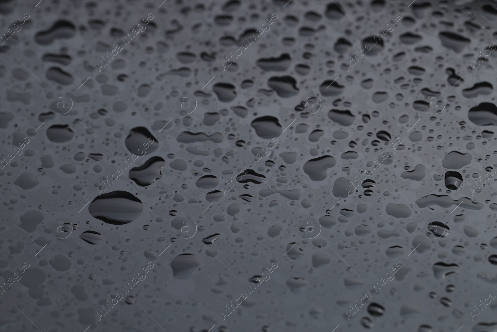 Photo of Water drops on grey glass surface, closeup