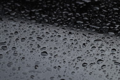 Photo of Water drops on grey glass surface, closeup