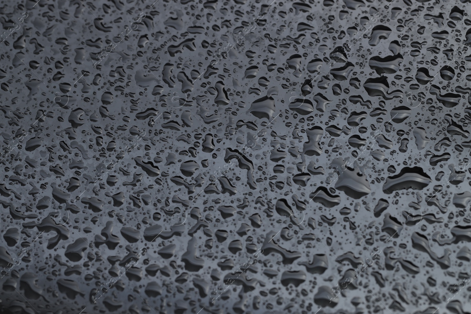 Photo of Water drops on grey glass surface, closeup