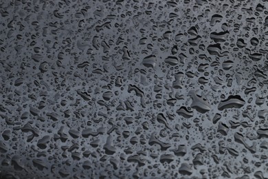 Water drops on grey glass surface, closeup